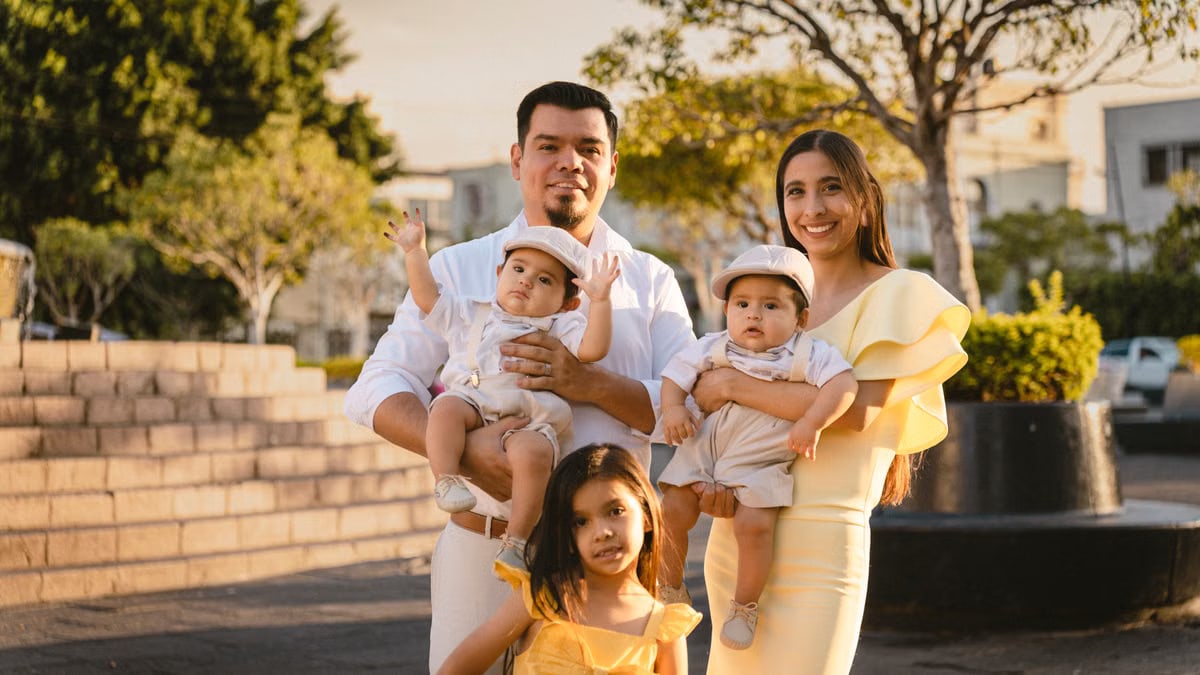 Smiling family with children posing outdoors in an urban park setting.